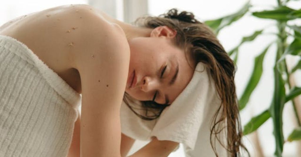 mujer secando su cabello después de limpiar el cuero cabelludo graso