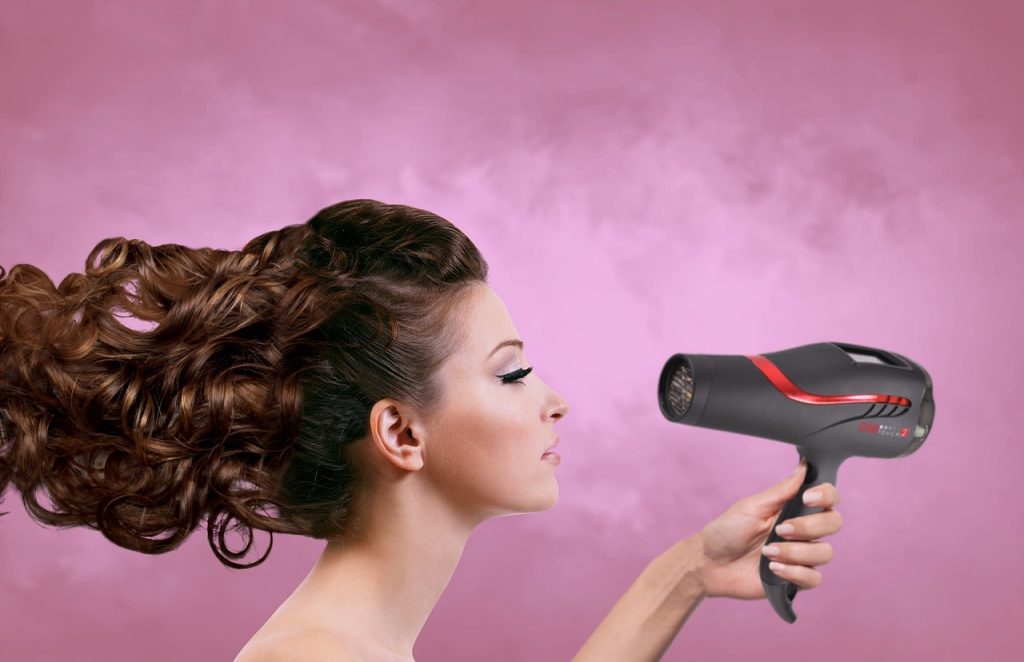 mujer aplicándose un secador para el cabello